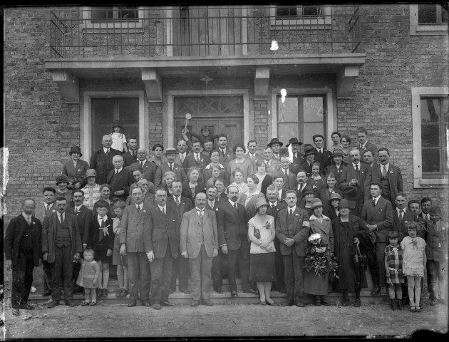 Groupe d'hommes, de femmes et d'enfants posant sur les escaliers d'un bâtiment en briques.