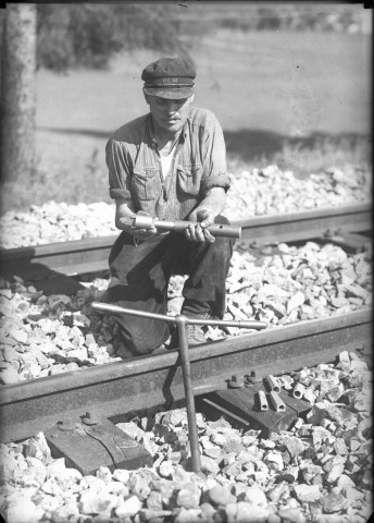 Homme faisant une démonstration avec des outils : plaque de verre 13x18 cm.Pose de rivets sur les traverses de chemin de fer.