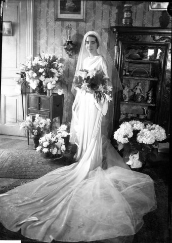 Une mariée debout prenant la pose une gerbe de lys dans ses bras (même cliché que 51 Fi 587) : négatif souple 12,6x17,6 cm.