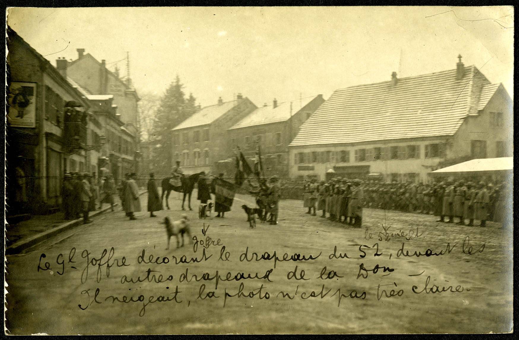 Giromagny, Grande Rue, revue du 140e Régiment d'Infanterie de
                                Ligne, décoration des drapeaux après la Bataille de Champagne par le
                                général Joffre.