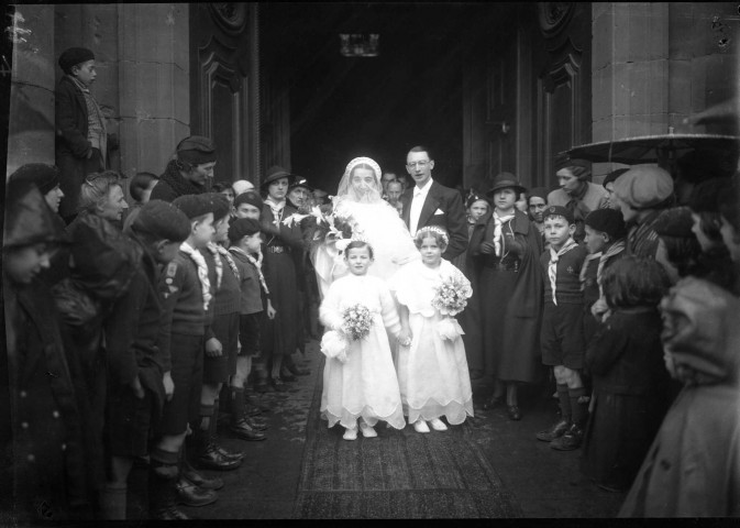 Couple de mariés sortant de l'église, escorté par une haie d'honneur formée de jeunes scouts : négatif souple 12,6x17,6 cm.
