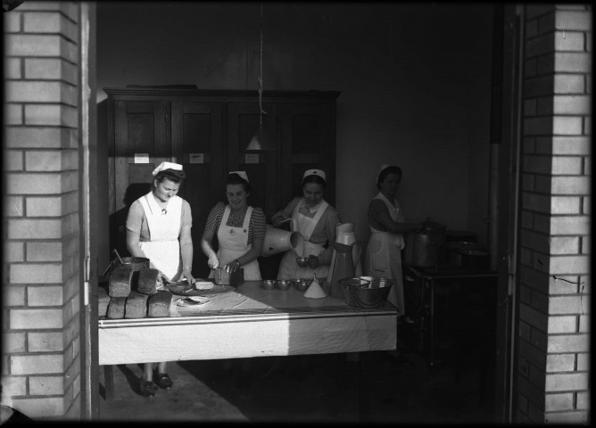 Dans un petit local en briques jaunes de la SNCF. Des infirmières préparent une distribution de tartines de pain et de lait.