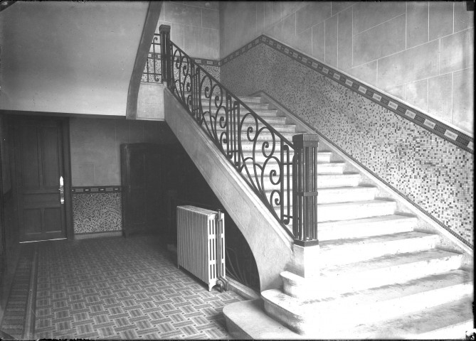 Escalier principal quart tournant menant aux salles de classe avec sa rampe en fer forgé : plaque de verre 13x18 cm.