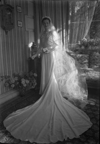 Dans un salon, la mariée debout prend la pose (même cliché que 51 Fi 526) : négatif souple 12,6x17,6 cm.