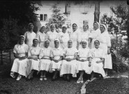 Assemblée d'infirmières assises sur deux rangs posant dans un square.