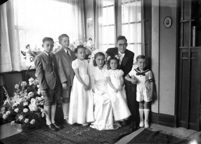 Couple de mariés assis entouré de cinq enfants d'honneur.