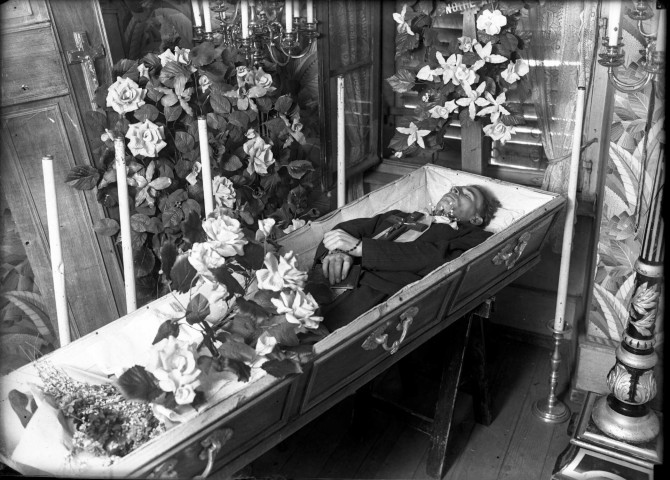 Dans un appartement aménagé en salon mortuaire, un homme repose dans son cercueil.