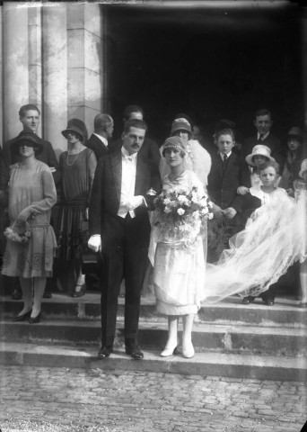 Sur les marches de l'église, un couple de mariés entouré d'une partie de ses invités.