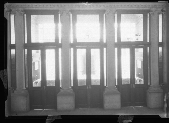 Portes d'entrées encadrées de quatre colonnes, trois portes battantes avec l'inscription location au milieu et loges et balcons & de côtes, côté droit. Cliché pris de l'intérieur : négatif souple 12,6x17,6 cm.