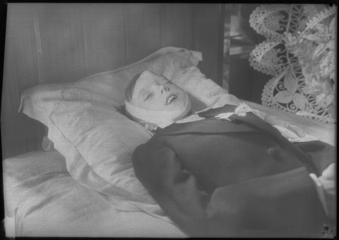 Sur son lit de mort, un bandage autour de la tête et une grosse bosse sur le front. Des couronnes de fleurs autour de lui : négatif souple 12,6x17,6 cm.