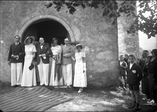 Devant une église, trois couples à la suite des mariés, garçons d'honneur et des badauds : plaque de verre 13x18 cm.