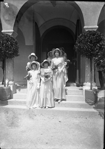 A la suite des mariés, quatre demoiselles d'honneur vêtues de robes longues et de capelines, posent sur le perron de la mairie.