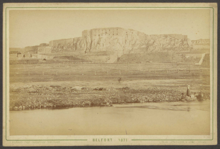 Belfort, faubourg de Montbéliard, vue générale depuis la rive de la Savoureuse (arrière du Couvent des Capucins), le Front de la porte de France (la tour bastionnée n°46 sans toiture), le château et ses fortifications, v. 1871.