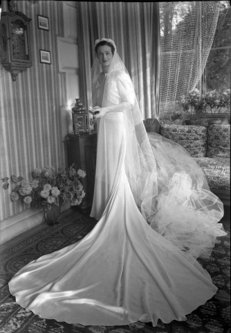 Dans un salon, la mariée debout prend la pose (même cliché que 51 Fi 526) : négatif souple 12,6x17,6 cm.