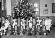 Scénette autour d'un arbre de Noël dans une salle de classe. Les jeunes élèves déguisés en lutins barbus tenant une lanterne : négatif souple 12,6x17,6 cm, [s.l.].