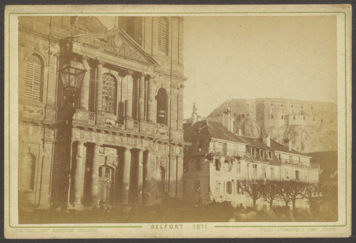Belfort, place d'Armes, la façade de l'église paroissiale catholique Saint-Christophe, façades d'immeubles d'habitation, les tilleuls de la fontaine, le château, v. 1871.
